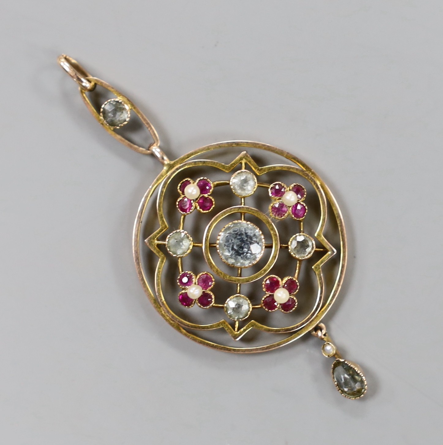 An Edwardian yellow metal, aquamarine, ruby and seed pearl set drop pendant, overall 55mm, gross weight 4.2 grams.